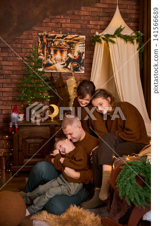family of four dressed in matching brown sweaters, gathered together in a rustic room with a exposed family of four dressed in matching brown sweaters, gathered together in a rustic room with a exposed 141566689