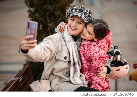 Mother and daughter taking selfie outdoors in winter 141566740