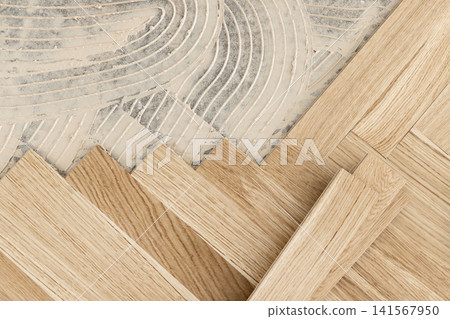 Oak herringbone parquet flooring installation with adhesive on concrete subfloor top view Oak herringbone parquet flooring installation with adhesive on concrete subfloor top view 141567950