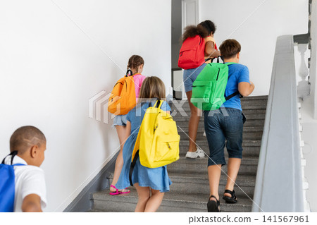 Diverse schoolchildren with colorful backpacks walking upstairs together inside school building Diverse schoolchildren with colorful backpacks walking upstairs together inside school building 141567961