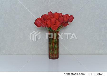 Beautiful tulip bouquet stands in glass vase on white table. Beautiful tulip bouquet stands in glass vase on white table. 141568629