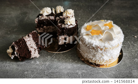 Delicious chocolate cake and sweet coconut treat placed on dark counter. Delicious chocolate cake and sweet coconut treat placed on dark counter. 141568814
