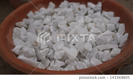 Terracotta pot with angular white stones and debris 141569605