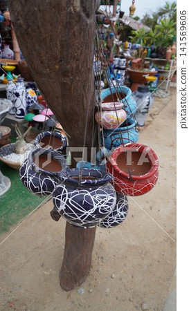 Colorful painted pots hang from wooden tree like trunk Colorful painted pots hang from wooden tree like trunk 141569606