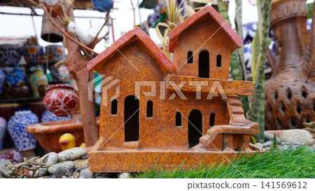 Two story clay birdhouse surrounded by small decorative rocks Two story clay birdhouse surrounded by small decorative rocks 141569612