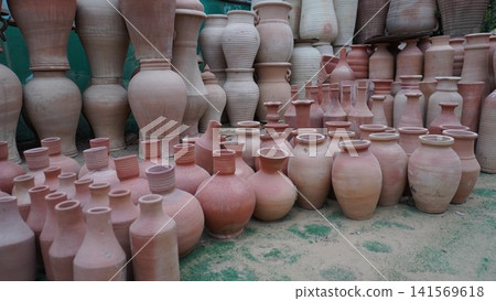 Many earthenware pots displayed on surface with greenery Many earthenware pots displayed on surface with greenery 141569618