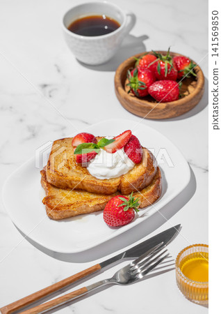 Brioche toasts with strawberries and whipped cream, drizzled with honey on a plate Brioche toasts with strawberries and whipped cream, drizzled with honey on a plate 141569850