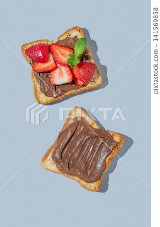 Two toasted slices with chocolate cream and strawberries on a blue isolated background Two toasted slices with chocolate cream and strawberries on a blue isolated background 141569858