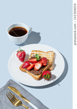 Toasted bread with chocolate cream and strawberry on a white plate on a blue background Toasted bread with chocolate cream and strawberry on a white plate on a blue background 141569859