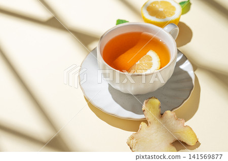 A cup of hot tea with fresh lemon, ginger, mint on a bright yellow background A cup of hot tea with fresh lemon, ginger, mint on a bright yellow background 141569877