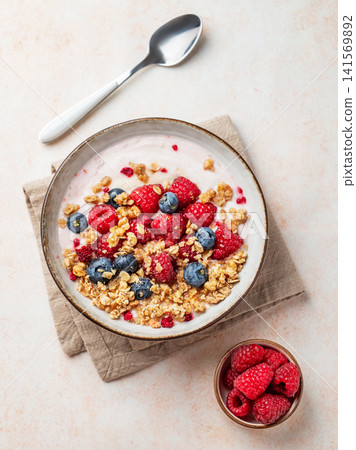 Natural greek yogurt with granola, blueberry and raspberry in a bowl on a light textured background Natural greek yogurt with granola, blueberry and raspberry in a bowl on a light textured background 141569892