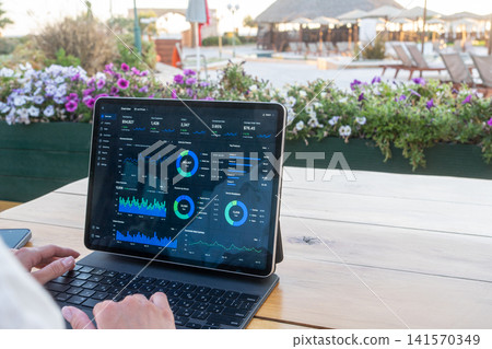 Close Up of Tablet Screen Displaying Business Analytics Dashboard at Outdoor Resort Cafe Close Up of Tablet Screen Displaying Business Analytics Dashboard at Outdoor Resort Cafe 141570349
