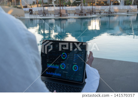 Over Shoulder View of Financial Analytics App on Tablet Screen Poolside Over Shoulder View of Financial Analytics App on Tablet Screen Poolside 141570357