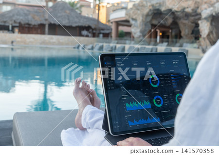 Over Shoulder View of Financial Analytics App on Tablet Screen Poolside Over Shoulder View of Financial Analytics App on Tablet Screen Poolside 141570358