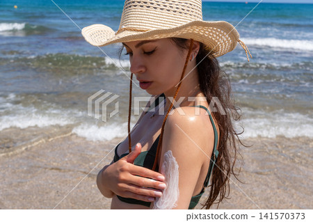 Close Up of Young Woman Applying Sunscreen Lotion on Her Shoulder at Beach Close Up of Young Woman Applying Sunscreen Lotion on Her Shoulder at Beach 141570373