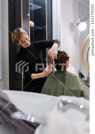 Young female hairdresser stylist working with scissors in beauty salon Stock Photo Young female hairdresser stylist working with scissors in beauty salon Stock Photo 141570500