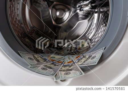 One hundred dollar bills inside open washing machine drum closeup 141570581