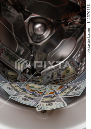 One hundred dollar bills inside open washing machine drum closeup One hundred dollar bills inside open washing machine drum closeup 141570588