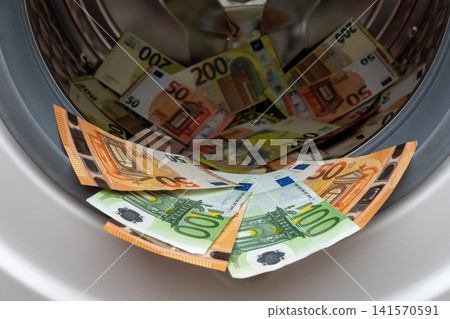 Euro banknotes inside open washing machine drum closeup Euro banknotes inside open washing machine drum closeup 141570591