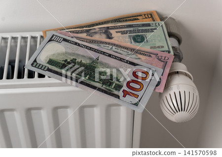US dollar banknotes on central heating radiator with thermostat valve US dollar banknotes on central heating radiator with thermostat valve 141570598