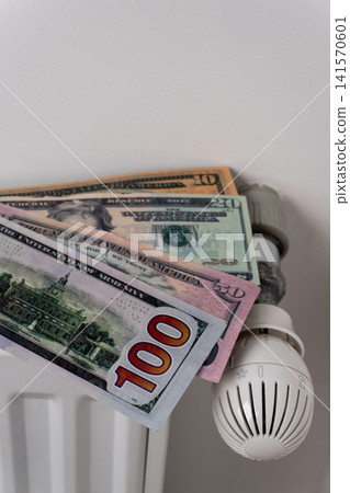 US dollar banknotes on central heating radiator with thermostat valve US dollar banknotes on central heating radiator with thermostat valve 141570601