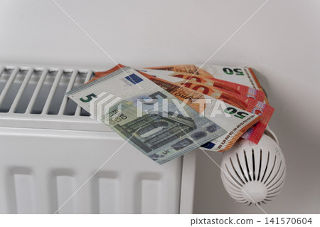 Euro banknotes on central heating radiator with thermostat valve Euro banknotes on central heating radiator with thermostat valve 141570604