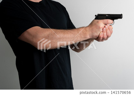 Man holding semi automatic pistol in shooting stance against plain background Man holding semi automatic pistol in shooting stance against plain background 141570656