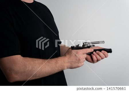 Man disassembling semi automatic pistol for maintenance on plain background Man disassembling semi automatic pistol for maintenance on plain background 141570661