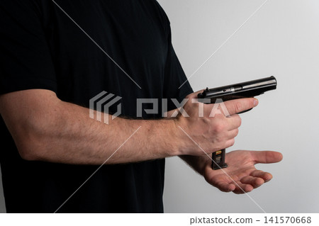 Man loading steel ammunition magazine into black handgun grip profile view Man loading steel ammunition magazine into black handgun grip profile view 141570668