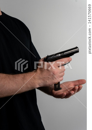 Man finishing magazine insertion into semi automatic handgun close up Man finishing magazine insertion into semi automatic handgun close up 141570669