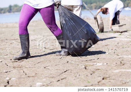 Collecting waste at river or lake coast Collecting waste at river or lake coast 141570719