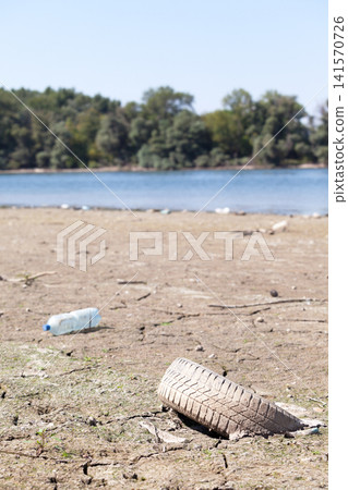 Old abandoned car tire lies on the river bank Old abandoned car tire lies on the river bank 141570726