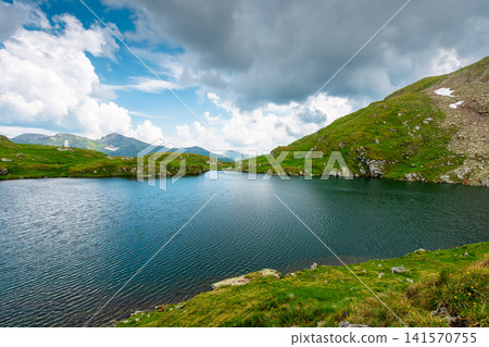 lake in romania mountain landscape. clear source of water. outdoor adventures in summer. cloudy sky over the fagaras ridge lake in romania mountain landscape. clear source of water. outdoor adventures in summer. cloudy sky over the fagaras ridge 141570755