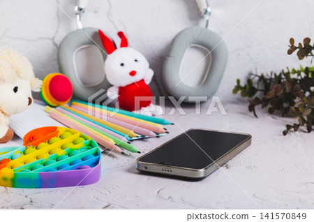 Smartphone, children's toys for leisure, album and pencils on the table Smartphone, children's toys for leisure, album and pencils on the table 141570849