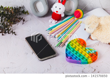 Social media ban concept for children. Smartphone and toys on the table. Social media ban concept for children. Smartphone and toys on the table. 141570850