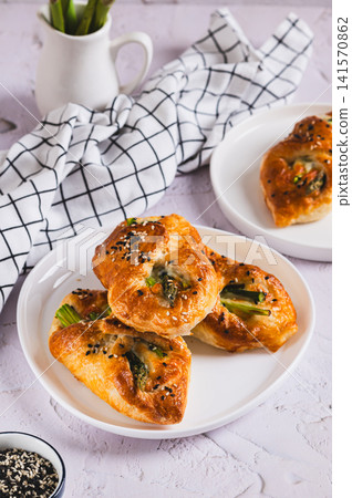 Asparagus baked in puff pastry with cheese and sesame seeds on a plate on the table vertical view Asparagus baked in puff pastry with cheese and sesame seeds on a plate on the table vertical view 141570862