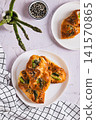 Asparagus baked in puff pastry with cheese and sesame seeds on a plate on the table top and vertical view 141570865