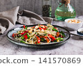 A delicious salad of glass noodles, fried bell peppers, cilantro, and nuts on a plate on the table 141570869