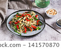 Rice noodles funchose with bell pepper, herbs and peanuts on a plate on the table 141570870