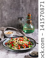 A delicious salad of glass noodles, fried bell peppers, cilantro, and nuts on a plate on the table vertical view 141570871