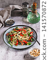 Rice noodles funchose with bell pepper, herbs and peanuts on a plate on the table vertical view 141570872