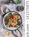 Rice noodles funchose with bell pepper, herbs and peanuts on a plate on the table top and vertical view 141570875