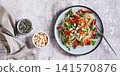 Rice noodles funchose with bell pepper, herbs and peanuts on a plate on the table top view web banner 141570876