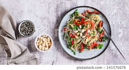 Rice noodles funchose with bell pepper, herbs and peanuts on a plate on the table top view web banner Rice noodles funchose with bell pepper, herbs and peanuts on a plate on the table top view web banner 141570876