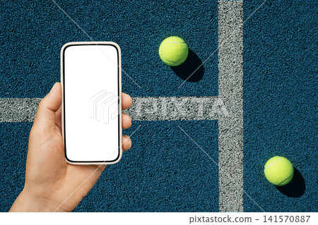 Smartphone mockup in hand on tennis court with balls Smartphone mockup in hand on tennis court with balls 141570887