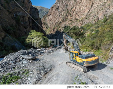 Excavator Working on Dirt Road in Rugged Canyon Excavator Working on Dirt Road in Rugged Canyon 141570945