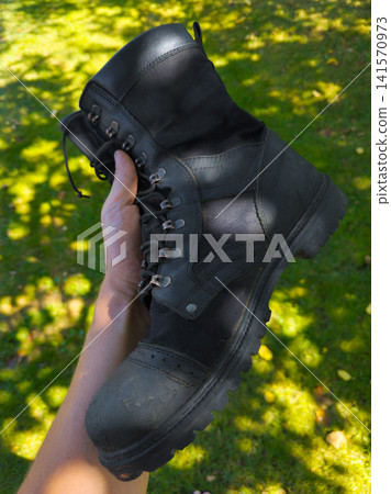 Hand Holding Black Work Boot in Outdoor Setting Hand Holding Black Work Boot in Outdoor Setting 141570973