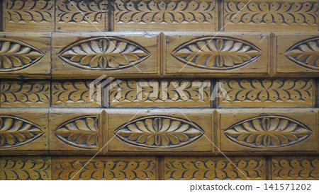 Detailed architectural pattern of carved wooden panels in a warm honey-gold color, craftsmanship concept. Detailed architectural pattern of carved wooden panels in a warm honey-gold color, craftsmanship concept. 141571202