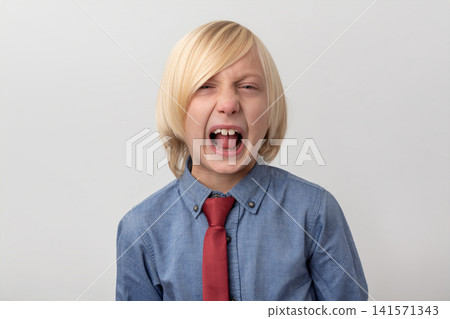 Blonde child in a blue shirt and red tie forcefully crying out and yelling, showing strong emotions like stress, pain, and discomfort against a white background Blonde child in a blue shirt and red tie forcefully crying out and yelling, showing strong emotions like stress, pain, and discomfort against a white background 141571343