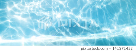 Sunlit pool water with shimmering blue reflections and rippling light patterns 141571432